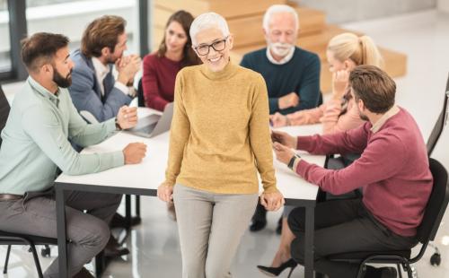 Woman standing in front of a group discussion around a table