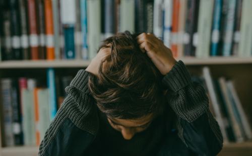 Boy with head in hands in a library