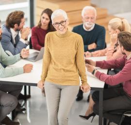 Woman standing in front of a group discussion around a table