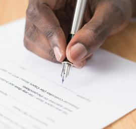 Person holding a pen signing a contract