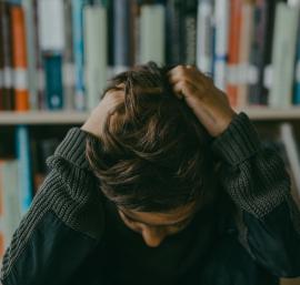 Boy with head in hands in a library
