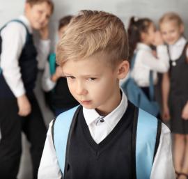 Child in the foreground with group of children whispering in the backgroun